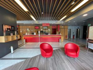 a waiting room with red chairs and a bar at Ibis Roma Fiera in Rome