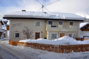 dom pokryty śniegiem z płotem w obiekcie Apart Claudia w mieście Nauders