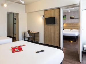 a hotel room with a bed and a tv at Ibis Centre Millau in Millau