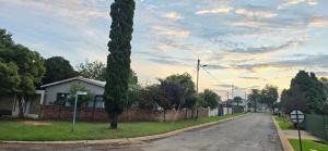 a house with a tree on the side of a street at Co operville in Potchefstroom