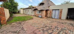 a brick house with a thatched roof on a driveway at Co operville in Potchefstroom