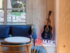a guitar hanging on a wall next to a couch at ibis Manosque Cadarache in Manosque