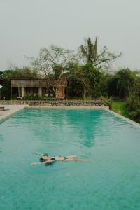 a woman laying in the water in a swimming pool at Sanctuary Chitwan National Park in Chitwan