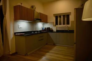 a kitchen with brown cabinets and black counter tops at Hotel Elysian By G K Group Near IGI Delhi Airport in New Delhi