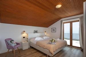 a bedroom with a bed with a purple chair and a window at Hillside Villa Kvarner: Pool & Sea View - Happy Rentals in Ičići