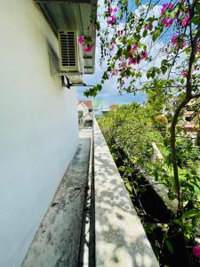 a walkway next to a white building with pink flowers at Balcony Garden Studio in Johor Bahru