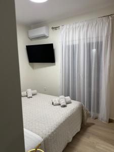a bedroom with a bed with white sheets and a tv at K&L Luxury Suite 2 in Parga