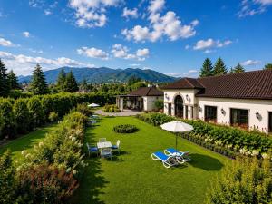 a house with a yard with chairs and an umbrella at Royal Cocoon - Nuwara Eliya in Nuwara Eliya