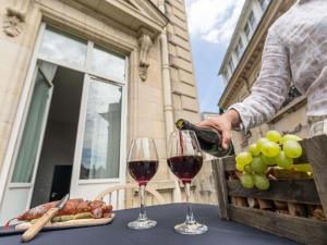 a person pouring wine into two glasses on a table at Mercure Le Mans Centre in Le Mans