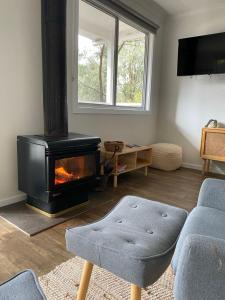 a living room with a fireplace and a couch and a chair at Noojee views - cozy studio in Noojee