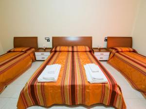 una camera d'albergo con tre letti e asciugamani di Hotel Villaggio S. Antonio a Isola Capo Rizzuto