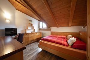 a bedroom with a red bed in a room with wooden ceilings at Apartments Rezia in Ortisei
