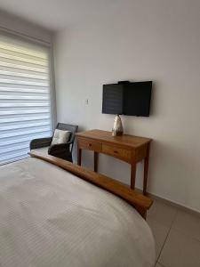 a bedroom with a bed and a table with a television at WHTheGardens in Pyla