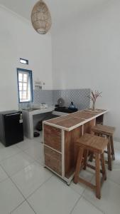 a kitchen with a counter and two wooden stools at Rumah Senden Guesthouse in Yogyakarta