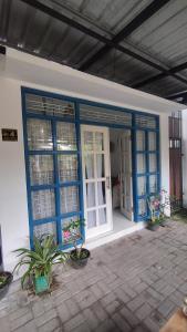 a house with blue doors and potted plants on a patio at Rumah Senden Guesthouse in Yogyakarta
