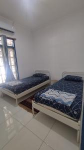 two beds sitting in a room with a window at Rumah Senden Guesthouse in Yogyakarta +2 photos