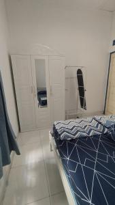 a bedroom with a bed and a mirror and a cabinet at Rumah Senden Guesthouse in Yogyakarta