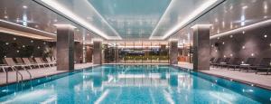 a large swimming pool in a building with chairs at DoubleTree By Hilton Seoul Pangyo in Seongnam