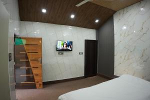 a bedroom with a tv on the wall and a bed at Saanjh Private Pool Villa Jaipur in Jaipur