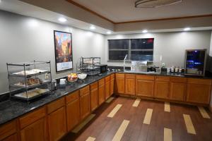 a kitchen with wooden cabinets and a counter with food at Ramada by Wyndham Tulsa Broken Arrow in Broken Arrow