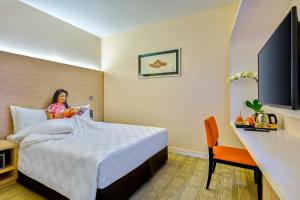 a woman sitting on a bed in a hotel room at Sama-Sama Express KLIA Terminal 2 - Airside Transit Hotel in Sepang