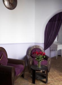 ein Wohnzimmer mit 2 Stühlen und einer Vase mit Blumen auf dem Tisch in der Unterkunft Casa Lila & Spa in Essaouira