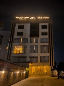 a white building with a sign on it at night at Briddhishree Palace in Guwahati