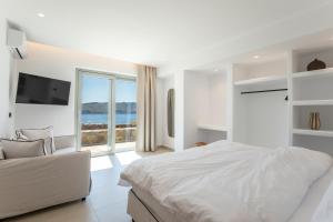 a white bedroom with a bed and a large window at Villa Sozon Mykonos in Agios Sostis Mykonos +58 photos