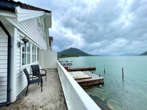 a porch of a house with a chair and the water at Fjord Apartments in Dimmelsvik