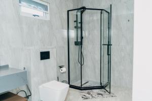 a glass shower in a bathroom with a toilet at The Gardens in Marracuene
