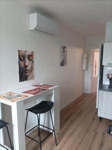 a white kitchen with a counter and a stool at T2 Cosy, agréable fonctionnel et douillet, 1 lit 140 et un BZ , Wifi gratuit, boîte à clés, proche commerces et gare routière, linge de lit et toilette offerts à partir de 4 nuits in Graulhet