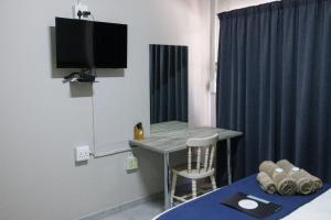 a room with a table and a television and a bed at Cosy Cottages Guesthouse in Potchefstroom