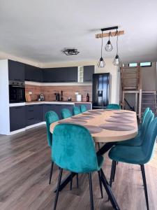a kitchen with a wooden table and green chairs at Hill House Marisel in Mărişel