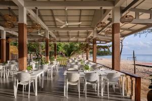 a restaurant on the beach with white tables and chairs at Sandy Beach Bungalows by EHM in Koh Rong Sanloem