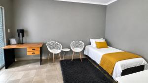 a bedroom with a bed with two chairs and a desk at Stay a While Self catering - Close to Greenacres Hospital, free Wi-Fi, and secure parking in Newton Park