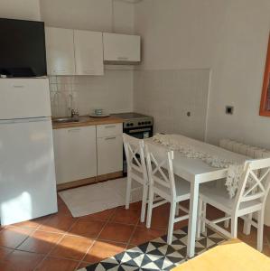 a kitchen with a white table and white chairs at Apartment Arte by in Pješčana Uvala