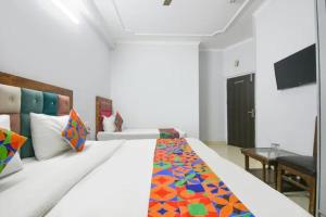 a bedroom with a large white bed with a colorful blanket at FabHotel Le Sancy in New Delhi +33 photos