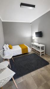a bedroom with a bed and a tv and a table at Stay a While Self catering - Close to Greenacres Hospital, free Wi-Fi, and secure parking in Newton Park