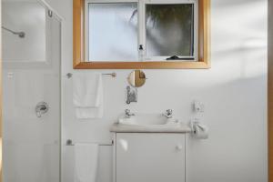 a white bathroom with a sink and a window at Sunlit Garden Granny Flat in Devonport