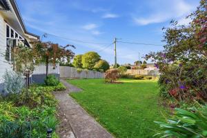 a yard with a fence and green grass at Sunlit Garden Granny Flat in Devonport +2 photos