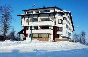 a large white building with snow in front of it at Apartment Hobbit - Bjelašnica in Bjelašnica