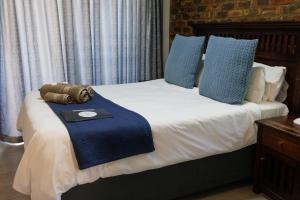 a bed with a blue blanket and pillows on it at Cosy Cottages Guesthouse in Potchefstroom +40 photos