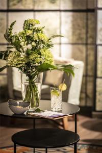 a vase of flowers on a table with a drink at Best Western Hotel Nürnberg am Hauptbahnhof in Nuremberg