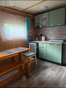 a kitchen with green cabinets and a wooden table at Tleniowo Domek in Tleń
