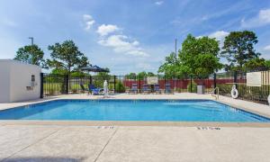 a swimming pool with chairs and an umbrella at Hampton Inn Houston-Pearland, TX in Pearland