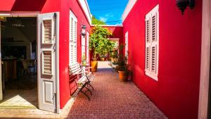 a red building with white doors and chairs on a street at Villa Tokara Boutique Hotel in Willemstad