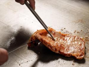 a person cutting a piece of meat with a knife at Hotel Vista Hiroshima in Hiroshima