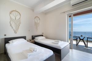 two beds in a room with a view of the ocean at Nirvana Homes in Vlachata
