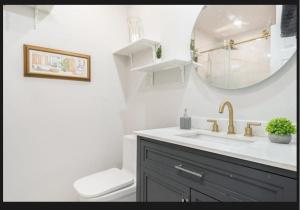 a bathroom with a sink and a toilet and a mirror at Family-Friendly Private Room With 2 Queen Beds in Brossard