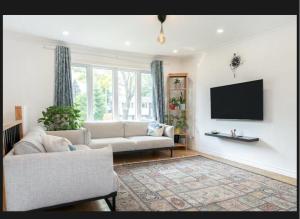 a living room with a couch and a flat screen tv at Family-Friendly Private Room With 2 Queen Beds in Brossard